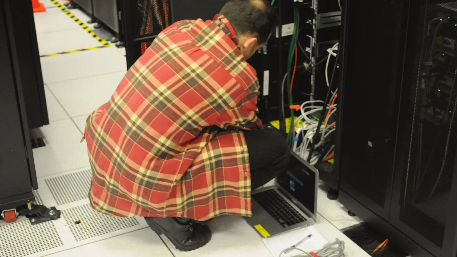 Teknisi memeriksa perangkat di rak server ruang data
